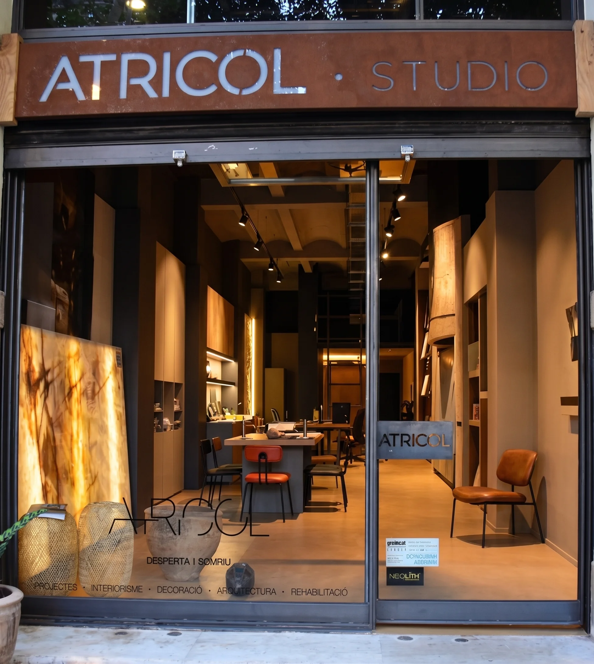 Exterior del showroom de Atricol Studio en Barcelona, con materiales decorativos visibles en el escaparate